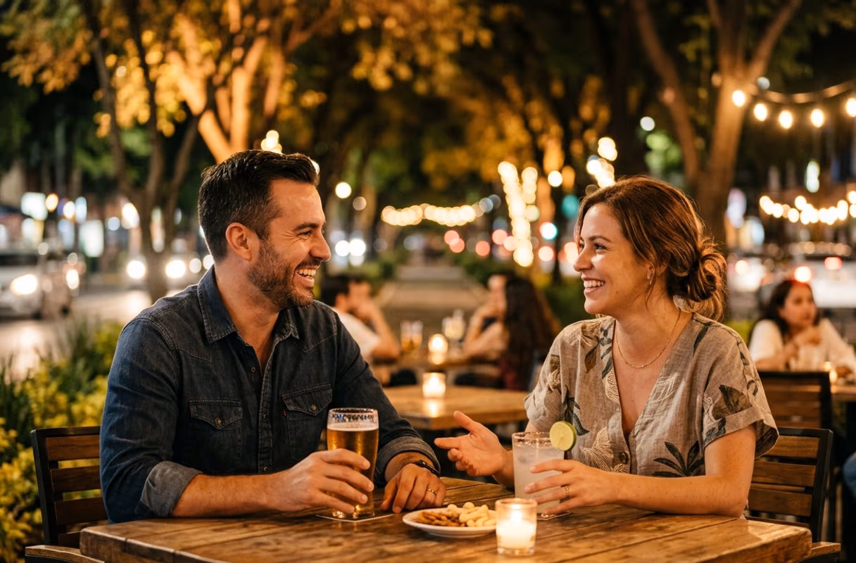 A couple talking over drinks at a bar table on Avenida Chapultepec in Guadalajara at night
