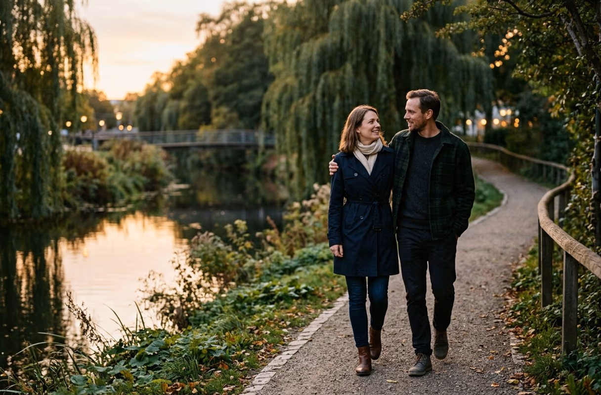 The Odense riverside at dusk — quiet and unhurried A couple walking close together along the green riverside path in Odense at dusk